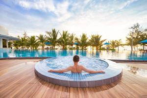 a man sitting in a pool at a resort at Langco Bay Retreat in Lang Co