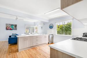 a kitchen with white walls and wooden floors at A Touch Of Paradise - 4 MIn Walk to Beach in Callala Beach