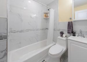 a white bathroom with a tub and a toilet and a sink at 233-3 - 4BR Boston - Peaceful Escape near Park Zoo in Boston +15 photos