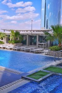 a pool with tables and chairs and a building at DAMAC Riyadh Residential apartments by SELSAL داماك الرياض in Riyadh
