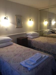 a hotel room with two beds and a mirror at Colnbrook Lodge Guest House in Slough