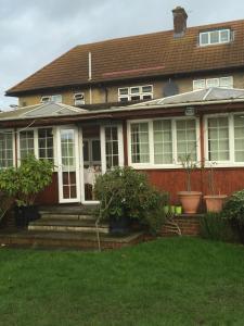 una casa marrón con porche y algunas plantas en Colnbrook Lodge Guest House, en Slough