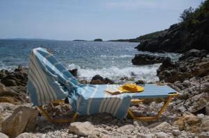 een stoel en een tafel op een rotsachtig strand bij Blue Marina in Sivota