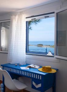 een blauw bureau met een raam met uitzicht op de oceaan bij Blue Marina in Sivota
