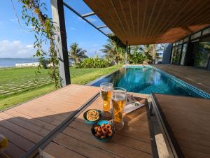a table with two glasses of beer next to a swimming pool at Ira Kabini by Luxunlock Private Villas in Antarasante