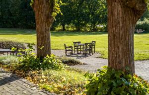 two picnic tables and benches in a park with trees at Lejl 50 in Skanderborg