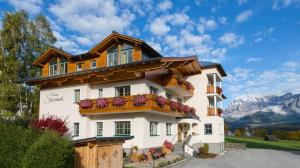 a building with flowers on the balconies and mountains at Pension Steiermark in Schladming