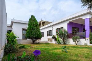 洛美Sublime modern villa的一栋白色房子，紫色镶边，带院子