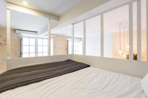 a white bed in a room with windows at Appartement St Michel in Bordeaux