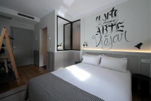 a bedroom with a white bed with a sign on the wall at H Complutum in Alcalá de Henares