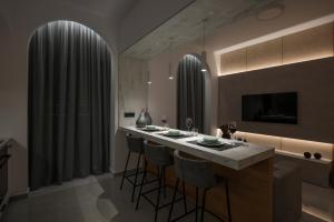 a kitchen with a bar with stools and a television at Amara Local Experience in Chania Town