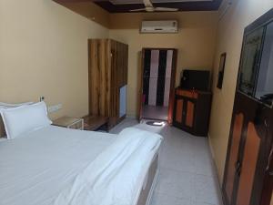 a bedroom with a large white bed and a television at Bhiwani Guest House in Jaipur