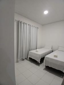 Una habitación blanca con dos camas y una ventana. en CHALÉS ENCANTOS DA ILHA, en Barra dos Coqueiros