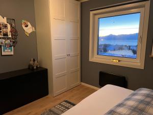 a bedroom with a window with a view of the water at Exclusive view villa in Tromsø