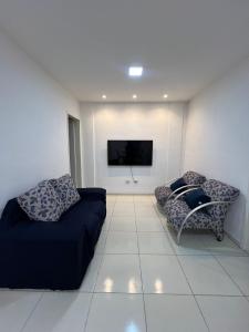 a living room with two couches and a flat screen tv at Apartamento Pé na areia no condomínio Manga Verde in Itamaracá