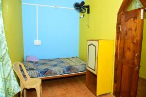 a small bedroom with a bed and a chair at Gajram Homestay Honnavar in Kāsarkod