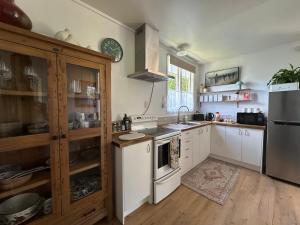 a kitchen with white appliances and wooden cabinets at The Quails Nest Cottage in Whakamarama