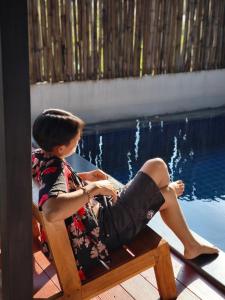 a young woman sitting on a chair next to a swimming pool at PoolVilla3 พักได้7ท่าน 3ห้องนอน4ห้องน้ำ in Doi Saket