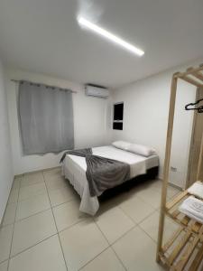 a white bedroom with a bed and a mirror at Apartamento Pé na areia no condomínio Manga Verde in Itamaracá +13 photos