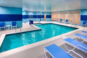 - une piscine avec des chaises bleues et une personne debout dans l'établissement Four Points by Sheraton Charleston, à Charleston