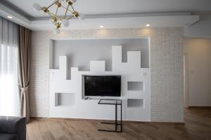 un soggiorno con TV su un muro di mattoni bianchi di Spartacus Apartments in Caesar Resort & SPA, Long Beach a Perivolia tou Trikomou Altre 23 foto