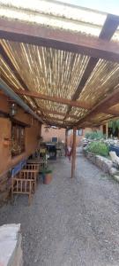 a patio with a wooden pergola with tables and benches at La Amanecida Tilcara in Tilcara
