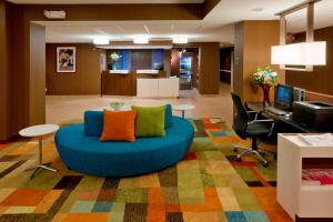 Una sala de estar con un sofá azul y un escritorio. en Fairfield Inn by Marriott East Rutherford Meadowlands, en East Rutherford