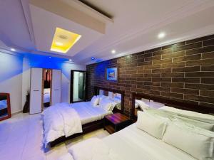 a bedroom with two beds and a brick wall at Hôtel Les Mamelles in Dakar