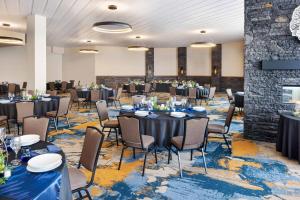 a banquet hall with tables and chairs and a stone wall at Delta Hotels by Marriott Grande Prairie Airport in Grande Prairie