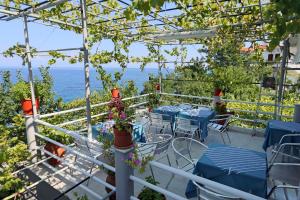 a patio with tables and chairs and the ocean at Sunset Studios in Skala Marion