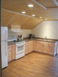 a kitchen with white appliances and wooden cabinets at Smithers Driftwood Lodge in Smithers