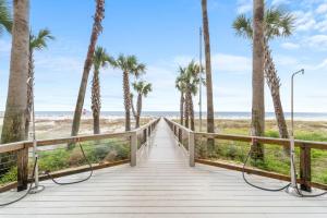a boardwalk leading to the beach with palm trees at Turquoise C702 in Orange Beach