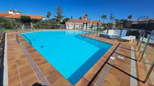 a large swimming pool with blue water in a yard at Bungalow BAHIA VERDE in Playa del Ingles