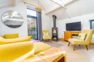 a living room with yellow furniture and a fireplace at Mill End by Big Skies Cottages in Weybourne