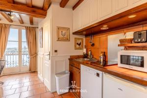 una cucina con mobili bianchi e un forno a microonde di Key West - charming studio ON the port of Honfleur - Superb 360 view a Honfleur