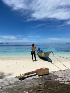 un hombre de pie junto a un barco en la playa en Biryei Homestay Raja Ampat, en Pulau Birie