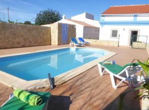 a large swimming pool with two chairs and a table at Ferienhaus Casa Limoeiro by fewo-plan ESTO101 an der Algarve in Azinheiro
