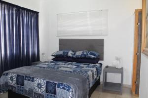 a bedroom with a bed with blue and white sheets and a window at Angel Cottage in Tzaneen