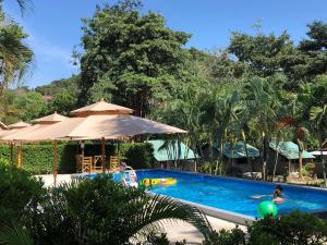 una piscina con sombrilla y gente en ella en Siam Flora Resort Koh Lanta, en Ko Lanta