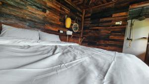 a white bed in a room with wooden walls at Sùng A Hờ Homestay in Mù Cang Chải