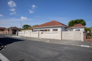 a white fence in front of a house at one bedroom apartment A1 in Cape Town