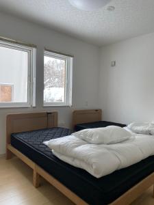 a bedroom with two beds and two windows at Niseko Yu Villa C in Niseko