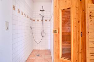 a bathroom with a shower with white tiles at Am Redensee in Fuhlendorf +16 photos