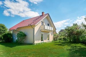 a white house with a balcony and a yard at Am Redensee in Fuhlendorf