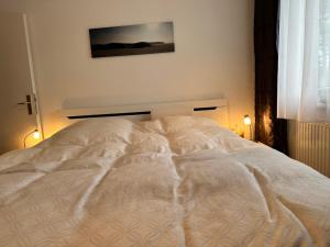 a large white bed in a bedroom with two lights at Küsten Koje in Sankt Peter-Ording