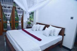 a bedroom with a white bed with white pillows at Ella Woodland 3 Arch Cottage in Ella +48 photos