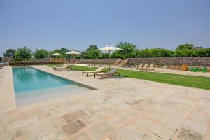 una piscina con bancos y sombrillas en un patio en Masseria Abbracciavento - Private Pool by HDSalento, en Tricase