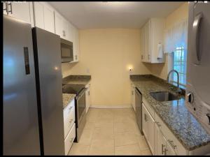 una cucina con mobili bianchi e un frigorifero in acciaio inossidabile di Charming 3 Bedroom 2 Bathroom and a lanai a Venice