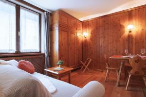 a room with a bed and a table and a dining room at GuestHost - Cortina Heart Retreat with Parking in Cortina dʼAmpezzo