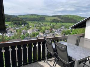 balcón con mesa y sillas y vistas a la ciudad en FeWo Pieck mit Parkplatz und privater Garage, en Winterberg